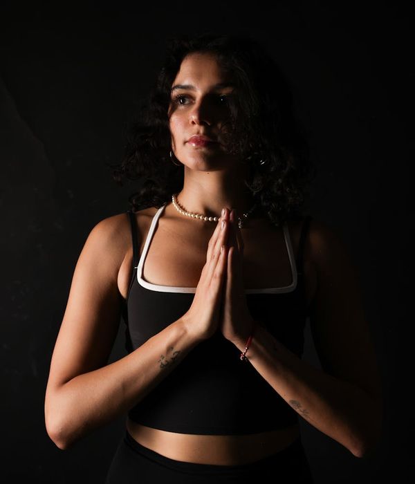 Woman in a calm yoga pose against a dark background.